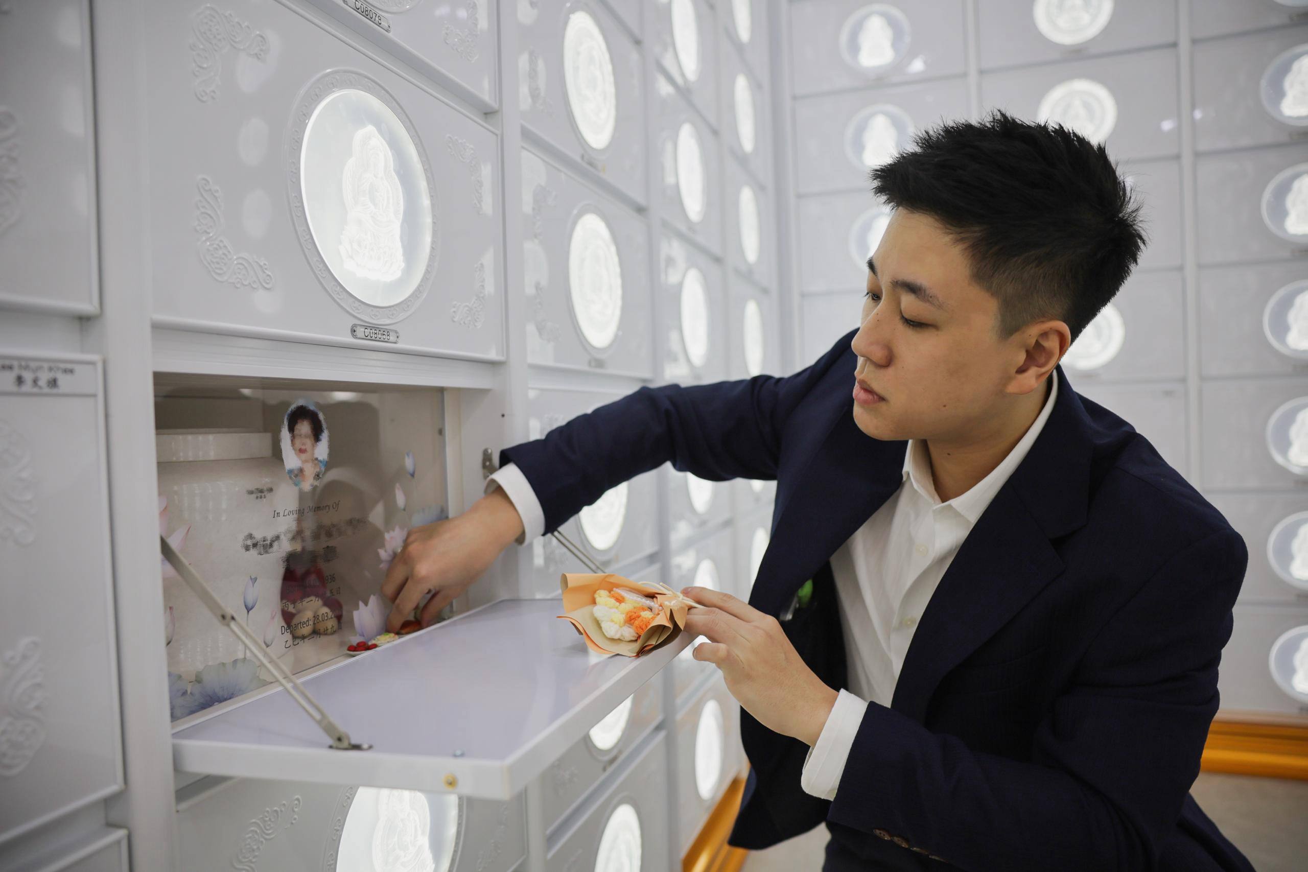 Kenneth Yeow arranging flowers at his grandmother's columbarium niche